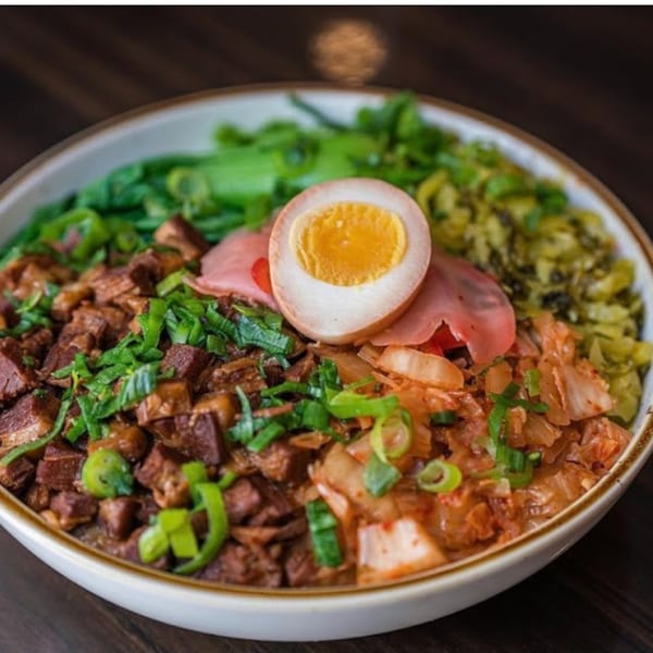 A bowl of Reren Lamen ramen with diced meat, kimchi, green vegetables, and a halved egg.